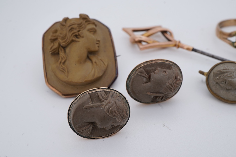 A collection of jewellery, comprising: a brooch, pair of earrings and a stick pin set with lava cameos; a stick pin capped with a geometric motif in gold, stamped 9CT; and a ring set with seed pearls and a garnet